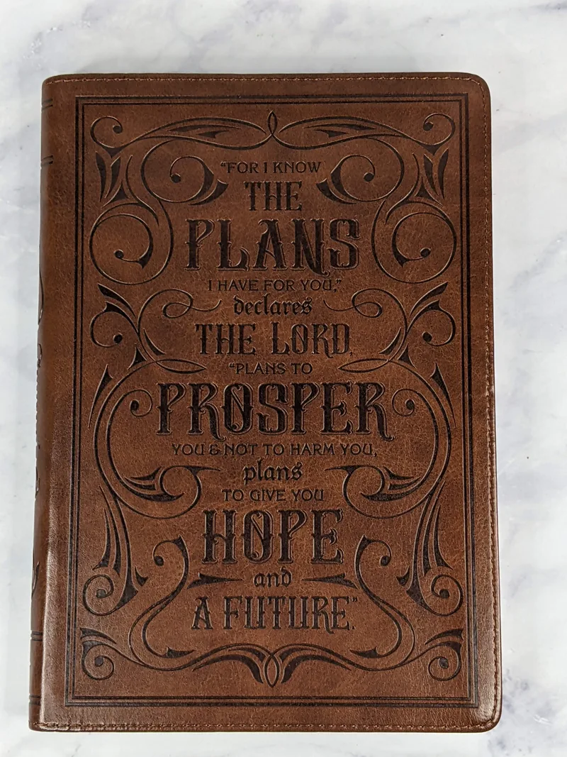 A Christian journal with a brown leather cover that features a Bible verse from Jeremiah 29:11.