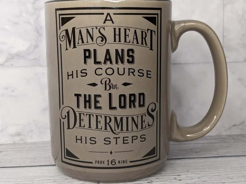 A religious mug for a man with a Bible verse. This coffee mug is tan with a black interior.