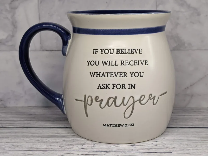 A blue and white religious coffee mug with a Scripture about prayer from Matthew 21:22.