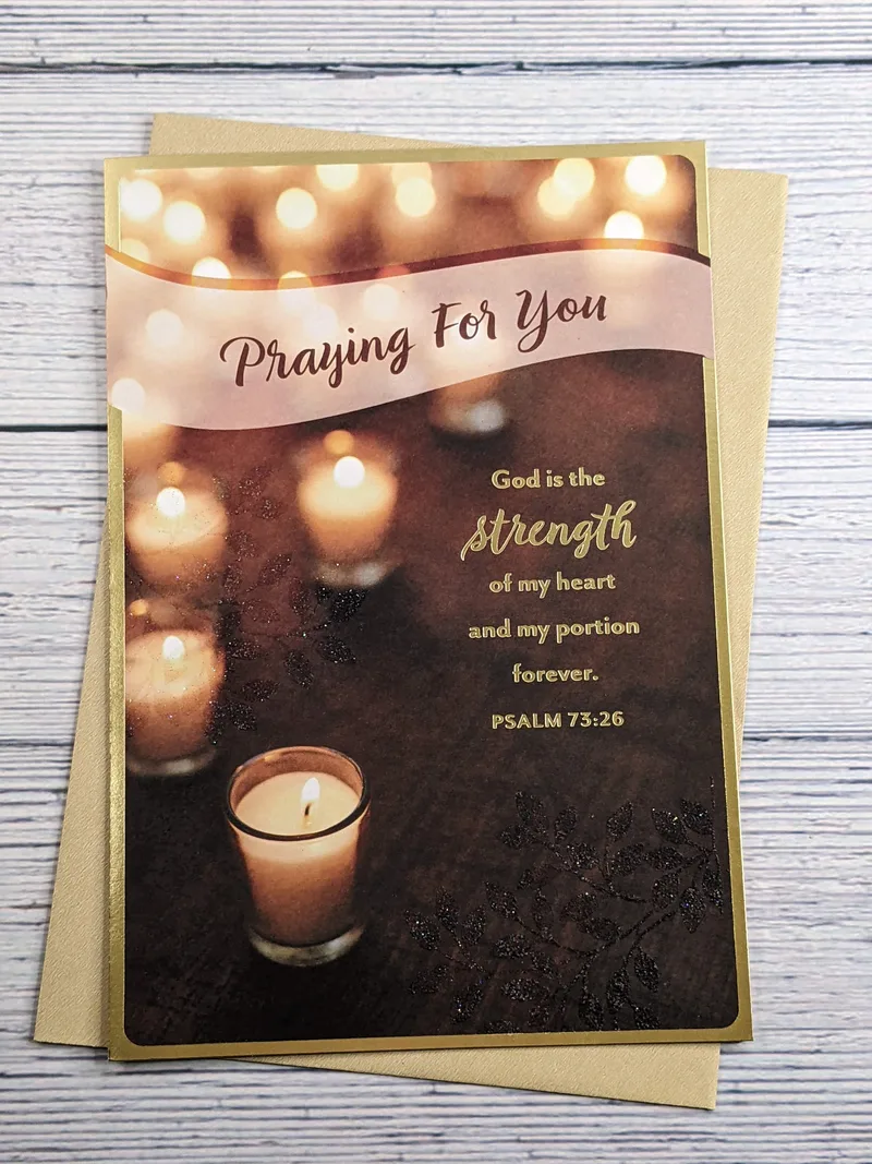 A religious encouragement card with a brown cover that has a Bible verse and an image of lit candles.