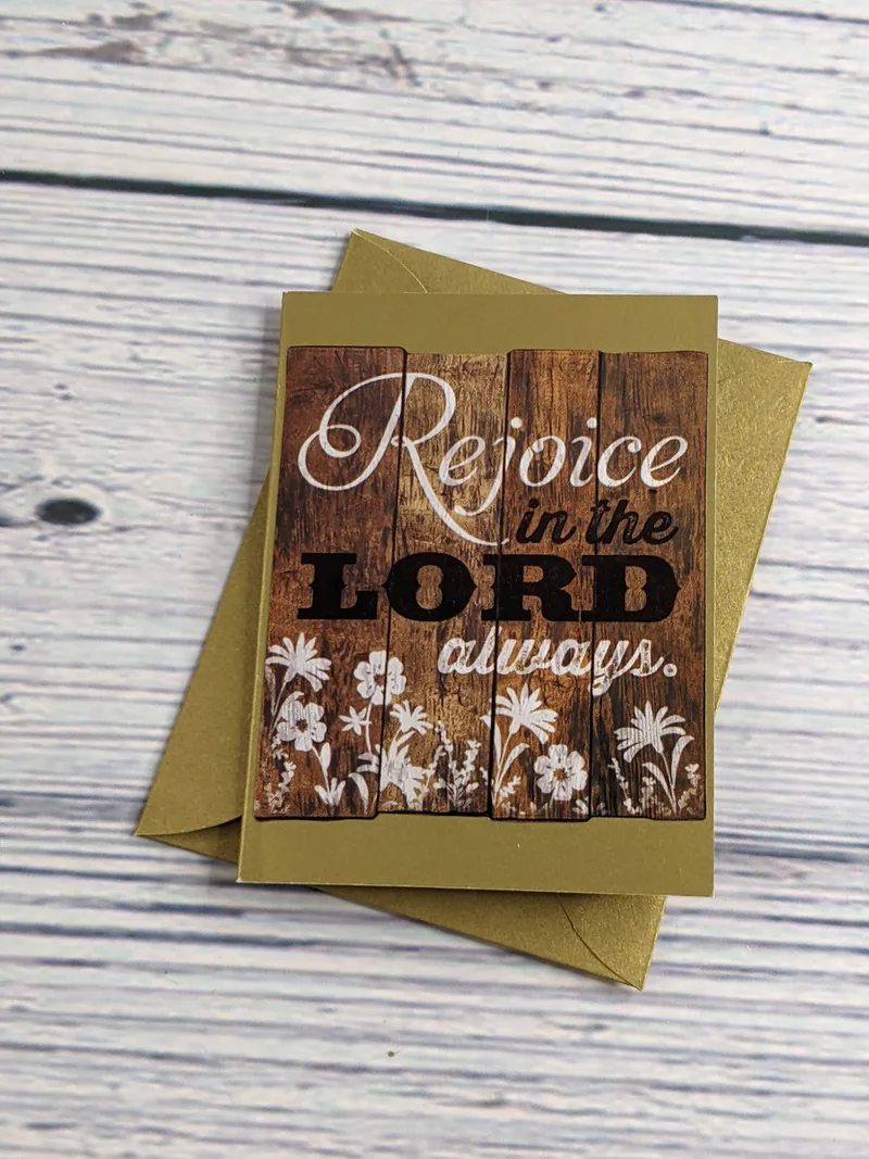 A mini greeting card with an envelope, gold colored with the Bible verse, "Rejoice in the Lord always."