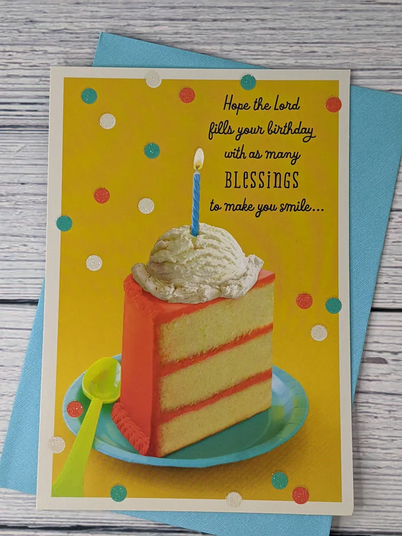 A Christian birthday card with a yellow cover that features an image of a slice of cake, topped with ice cream and a candle.
