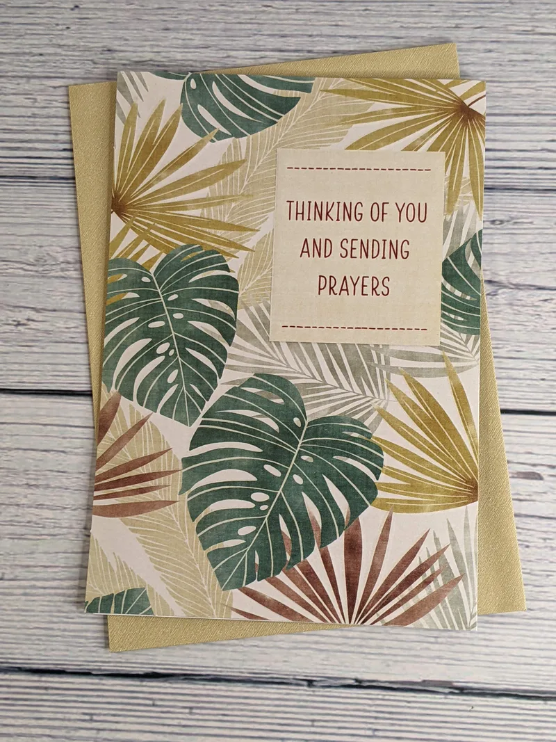 A tan and green sympathy greeting card with a design of leaves on the cover.