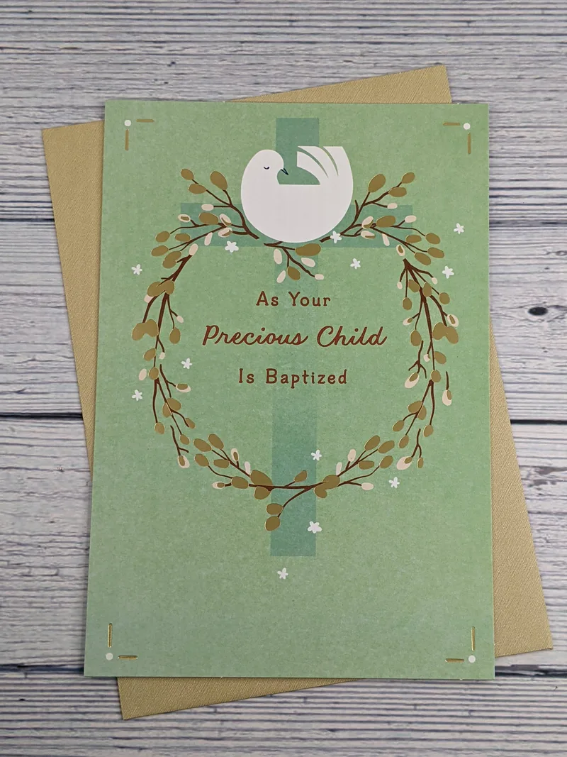 A religious baptism greeting card for a child with a green front that has an image of a white dove sitting on a golden wreath.