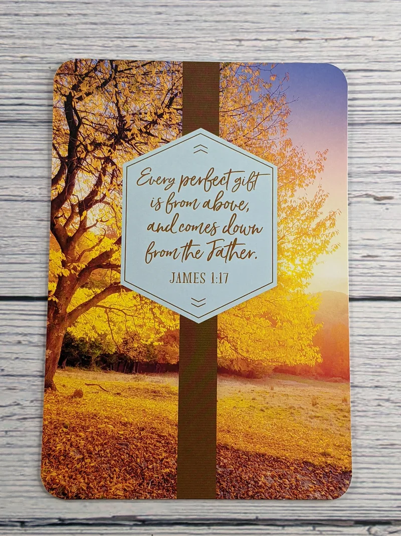 A Thanksgiving card with a Fall scene of a tree with fallen golden leaves, with a Bible verse on the cover.