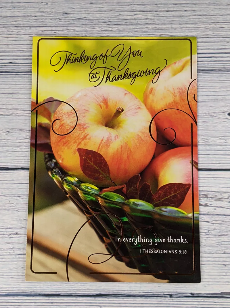 A Thanksgiving greeting card with an image of apples in a blue and green glass bowl with a Scripture on the front.