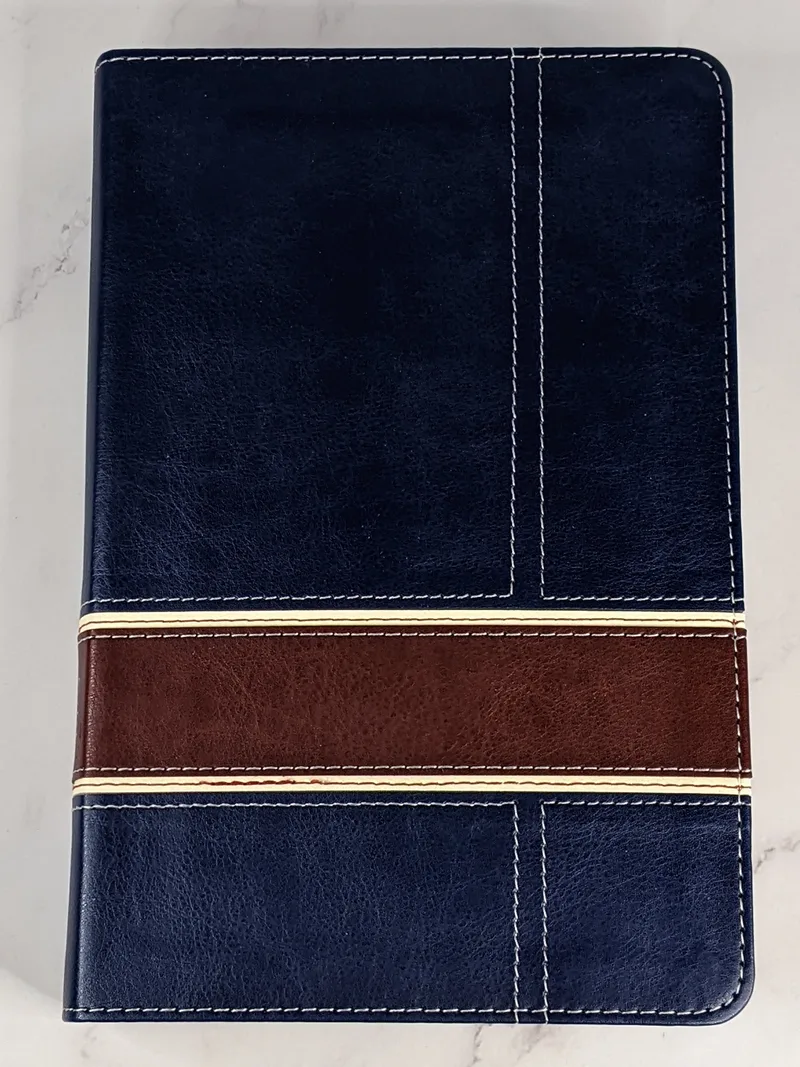 The Military Families Bible with a navy-blue leather-like cover has a burgundy stripe across the front.