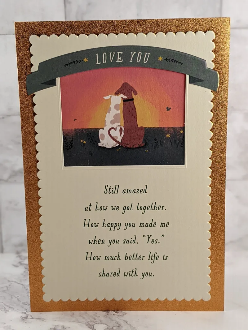 A religious anniversary card for a spouse with an image of two dogs snuggling on the cover.