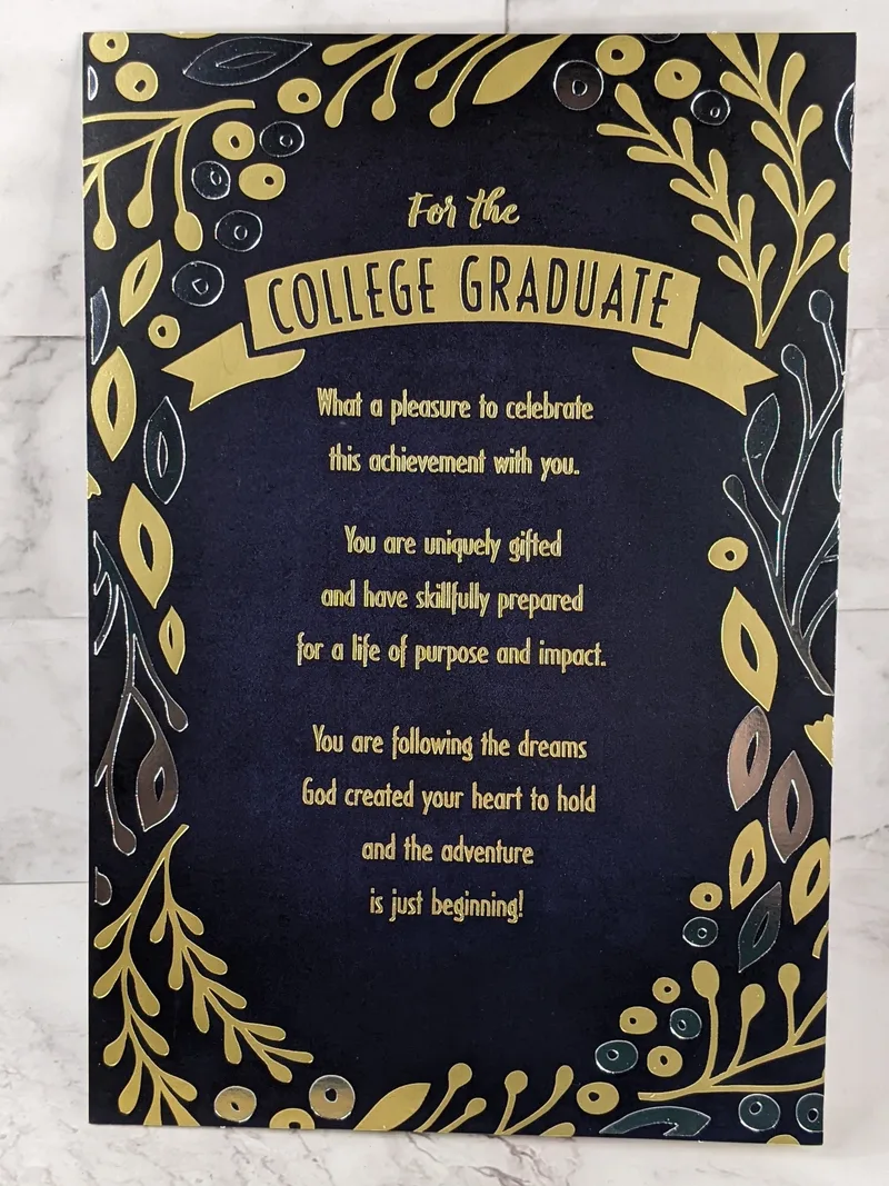 A college graduation card with a religious message. The front cover is black with gold lettering and a gold leaf design.