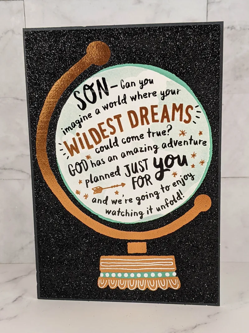 A graduation greeting card for a son with a glittery black background and an image of a globe on the cover.