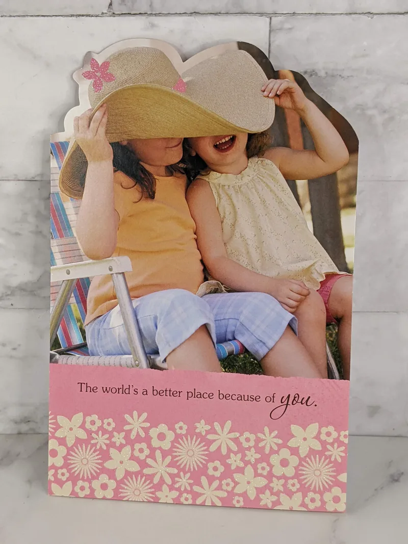 A religious friendship greeting card that features an image of two girls together wearing a huge hat.