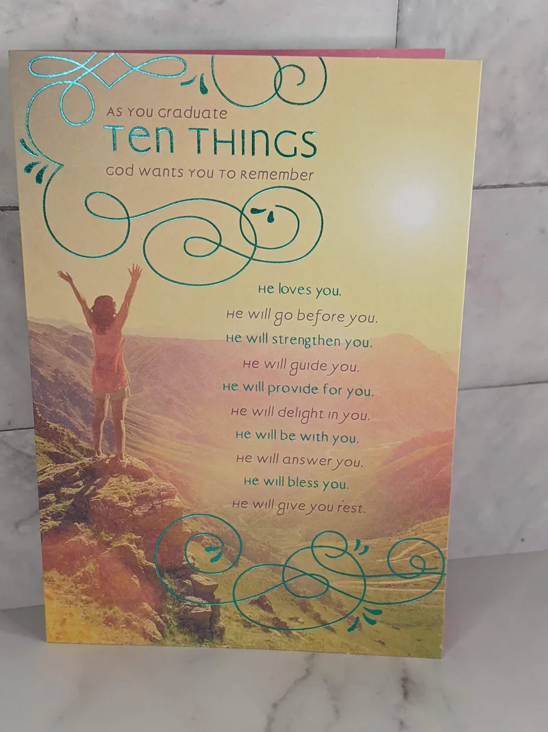 A religious grad card with scenic sunrise view from a mountaintop with a young woman reaching up with her hands.