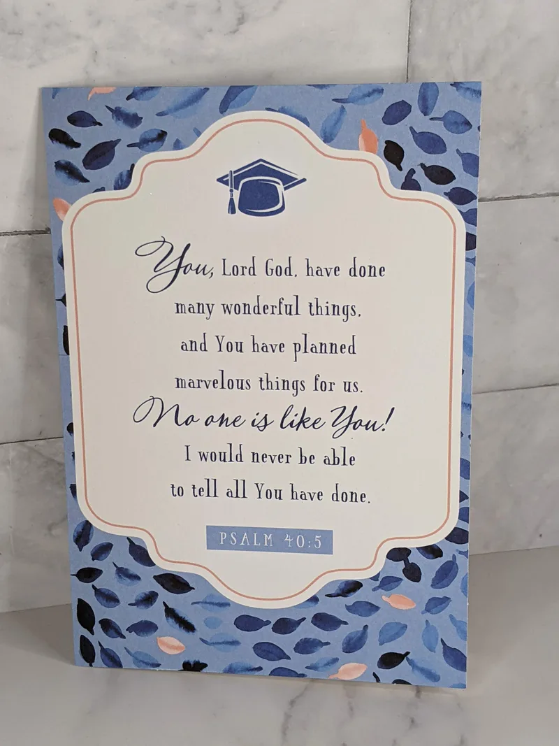 A blue and white graduation card with a religious message and an image of a graduate's cap.