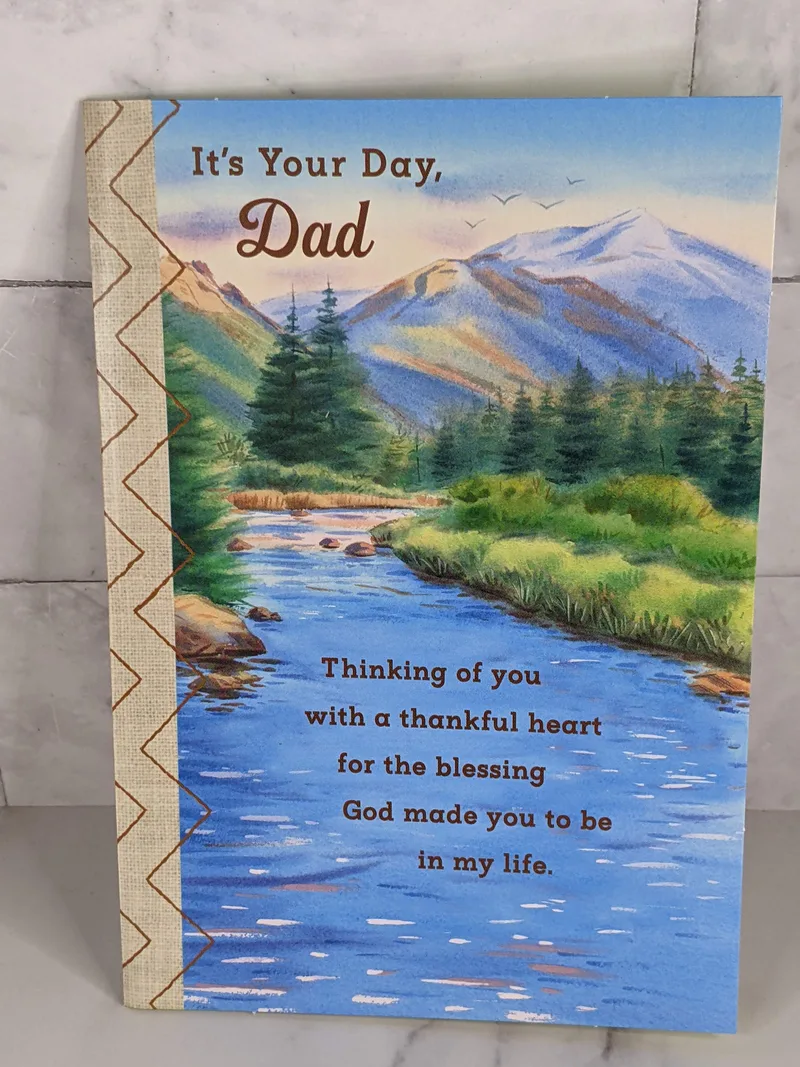 A religious Father's Day greeting card with scenic mountain view from a lake or river.