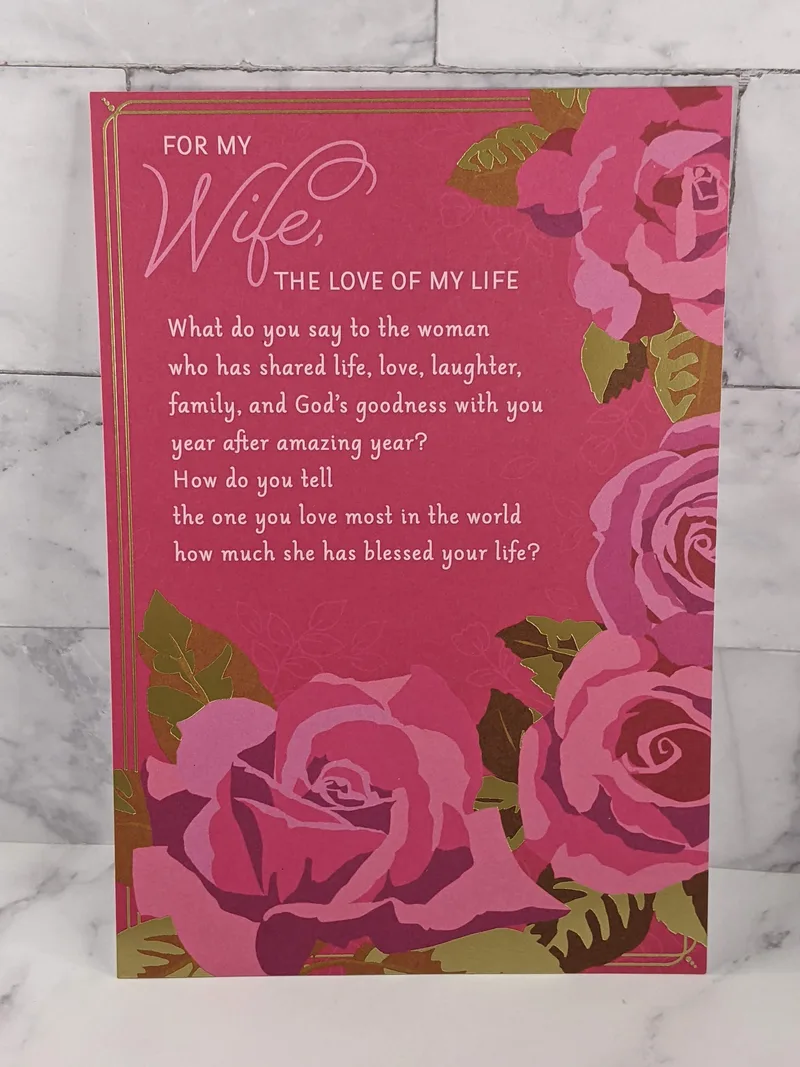 A pink religious anniversary card for a wife with images of pink roses on the cover.