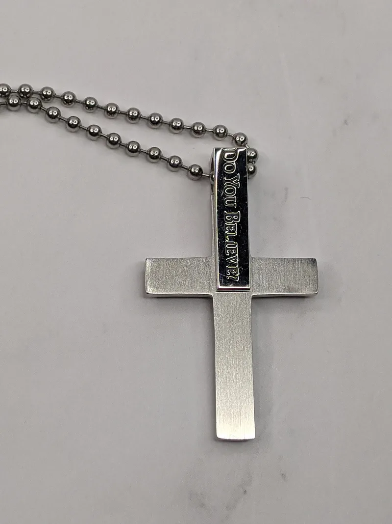 A silver chain necklace with a stainless-steel cross pendant that references a Bible verse.