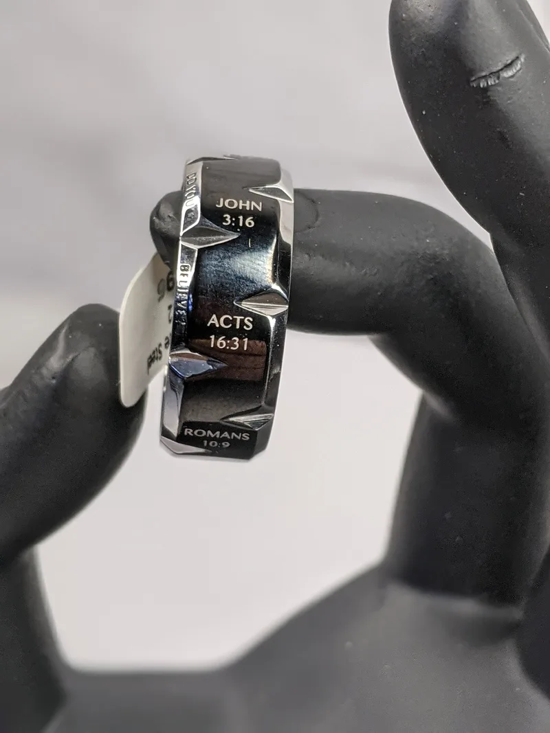 A silver ring for a man with a notched design and a black enamel coating with inscribed references of Bible verses.