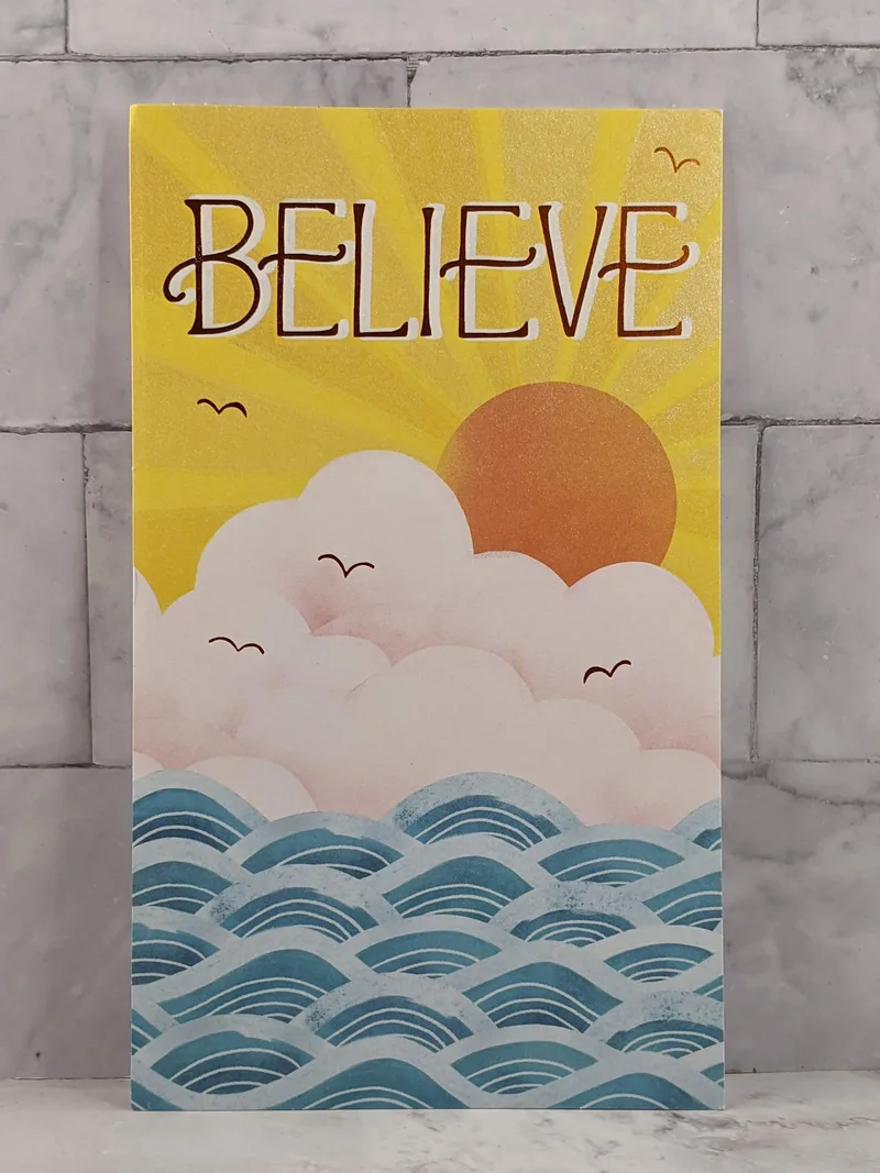 A faith-themed graduation card with an image of a yellow sunrise and the word, "Believe."