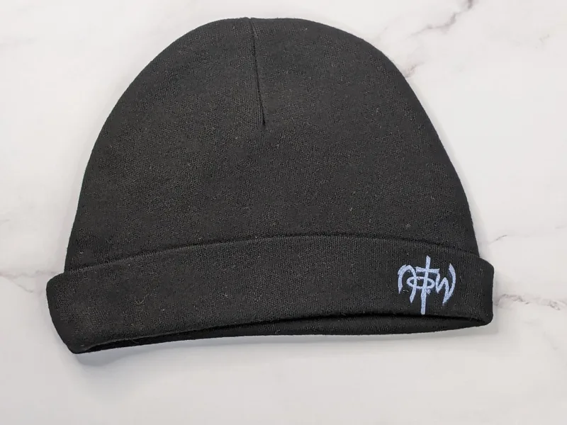 A black knit baby hat with a NOTW logo.