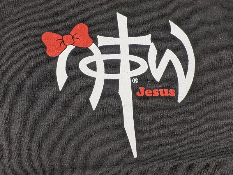 A one-piece baby outfit shirt that is black with a NOTW logo and a red bow design.