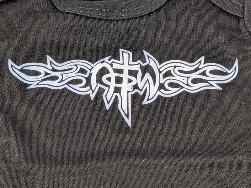A one-piece baby outfit shirt that is black with a NOTW logo and a white design of flames.