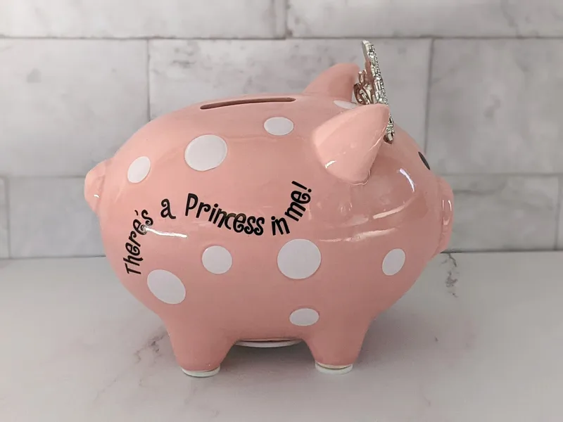 This cute pink coin bank is shaped like a pig wearing a crown, and features the words, "There's a princess in me."